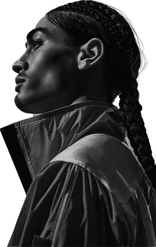 Retrato em preto e branco de um homem de perfil, com tranças longas e jaqueta escura.